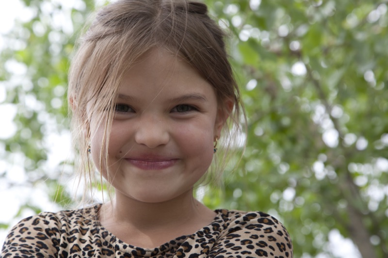 Abigail as a young girl, smiling under a tree